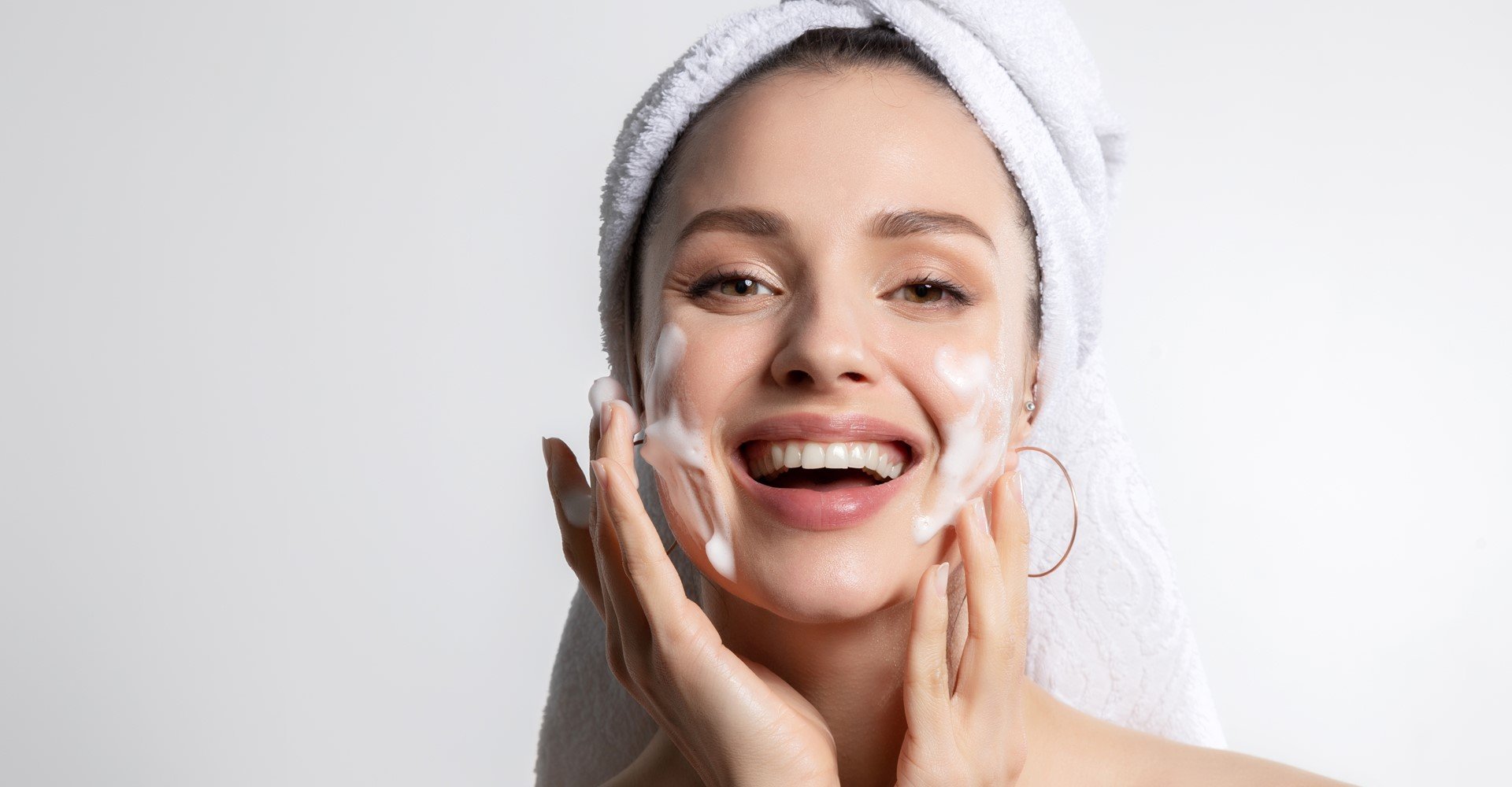 mulher sorrindo passando creme em seu rosto