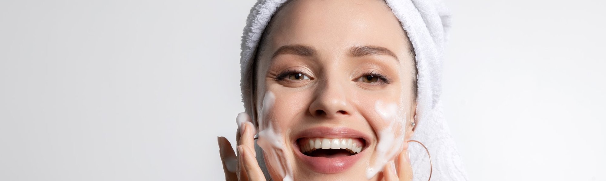 mulher sorrindo passando creme em seu rosto