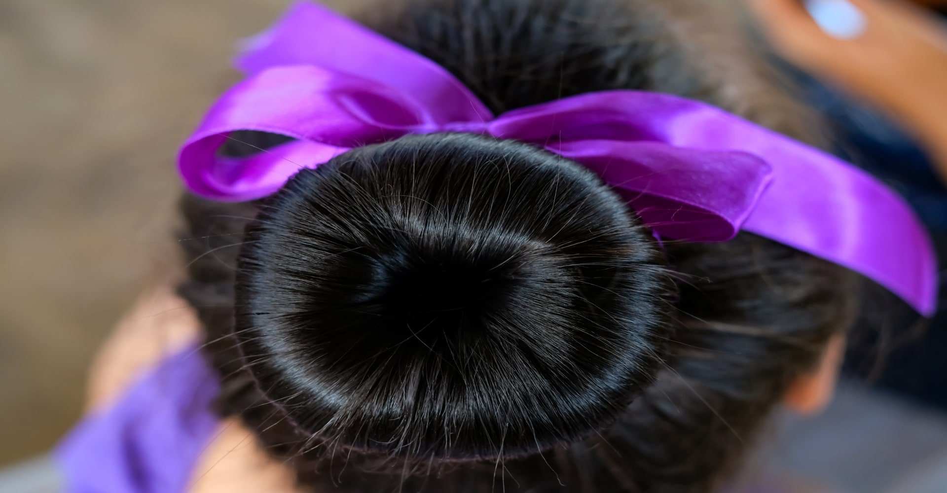 Coque em cabelo preto com uma fita roxa