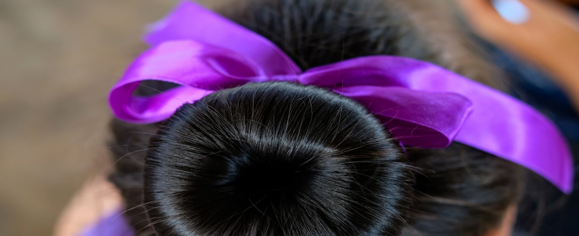 Coque em cabelo preto com uma fita roxa