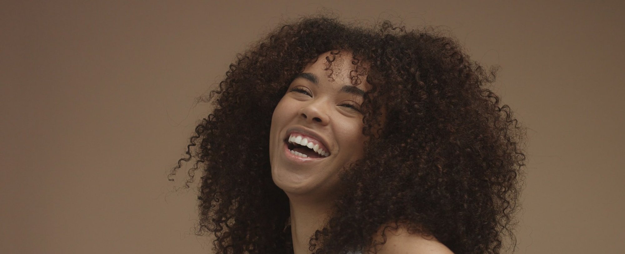 Modelo negra sorrindo com cabelo crespo