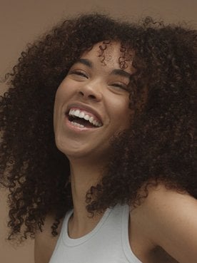 Modelo negra sorrindo com cabelo crespo