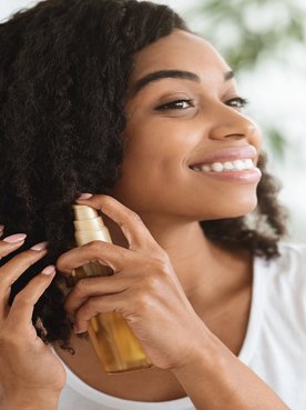 Modelo Negra Sorrindo E Passando Produto Em Seus Cachos