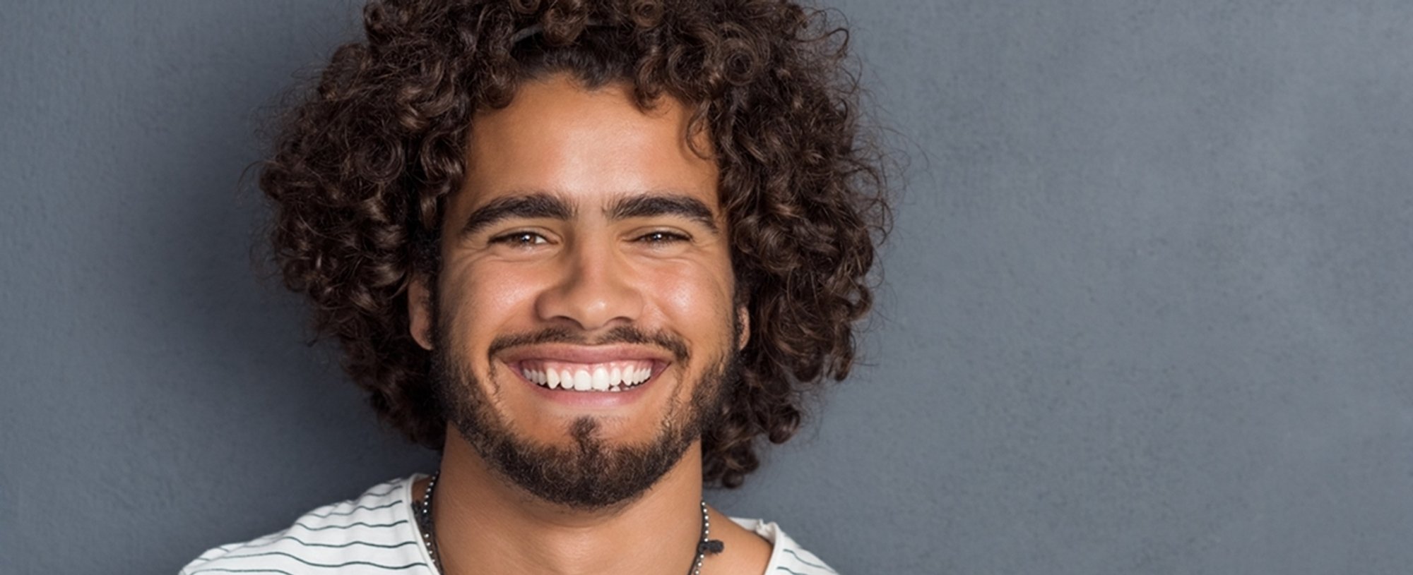 Imagem de um homem com cabelo cacheado, sorrindo.