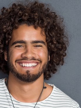 Imagem de um homem com cabelo cacheado, sorrindo.