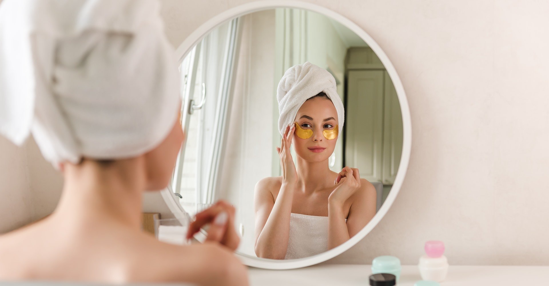 Modelo branca com toalha na cabeça se olhando no espelho