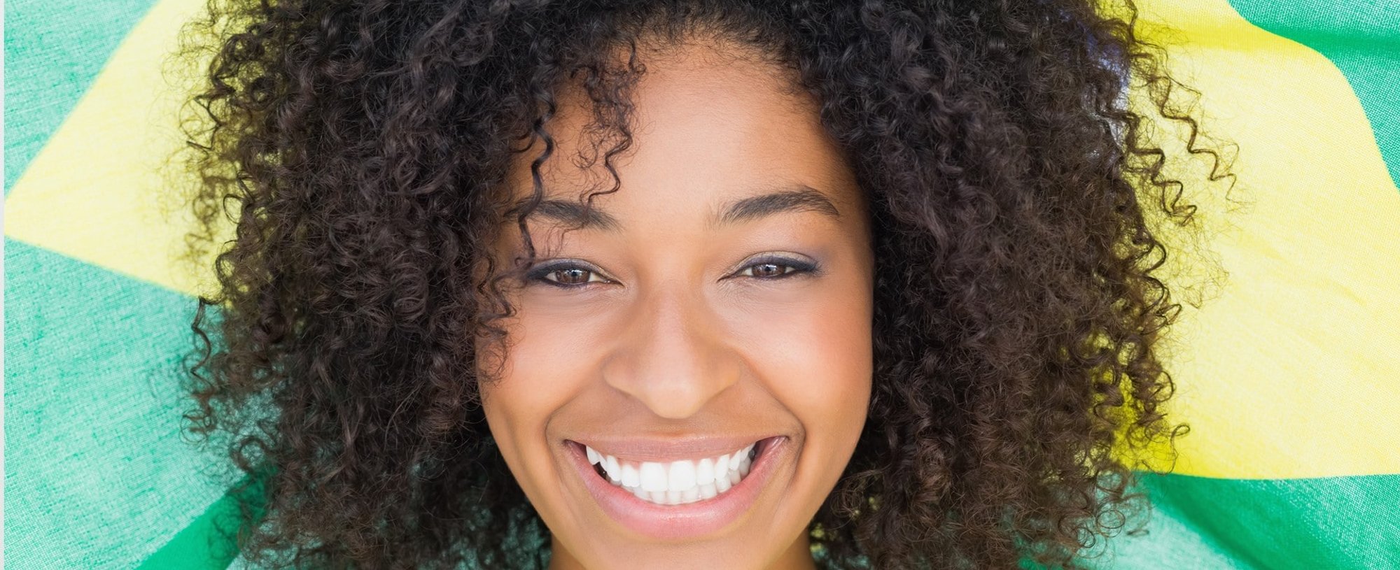Modelo negra sorrindo com cabelo cacheado