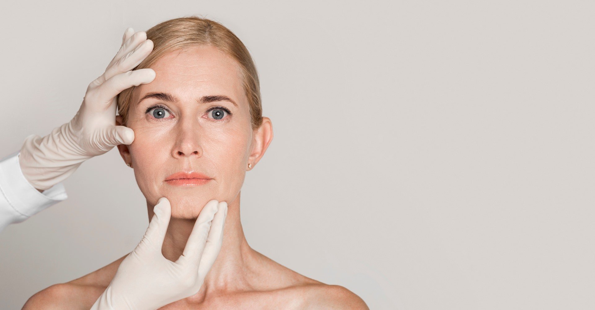 Profissional analisando rosto de modelo branca e loira com cabelo amarrado