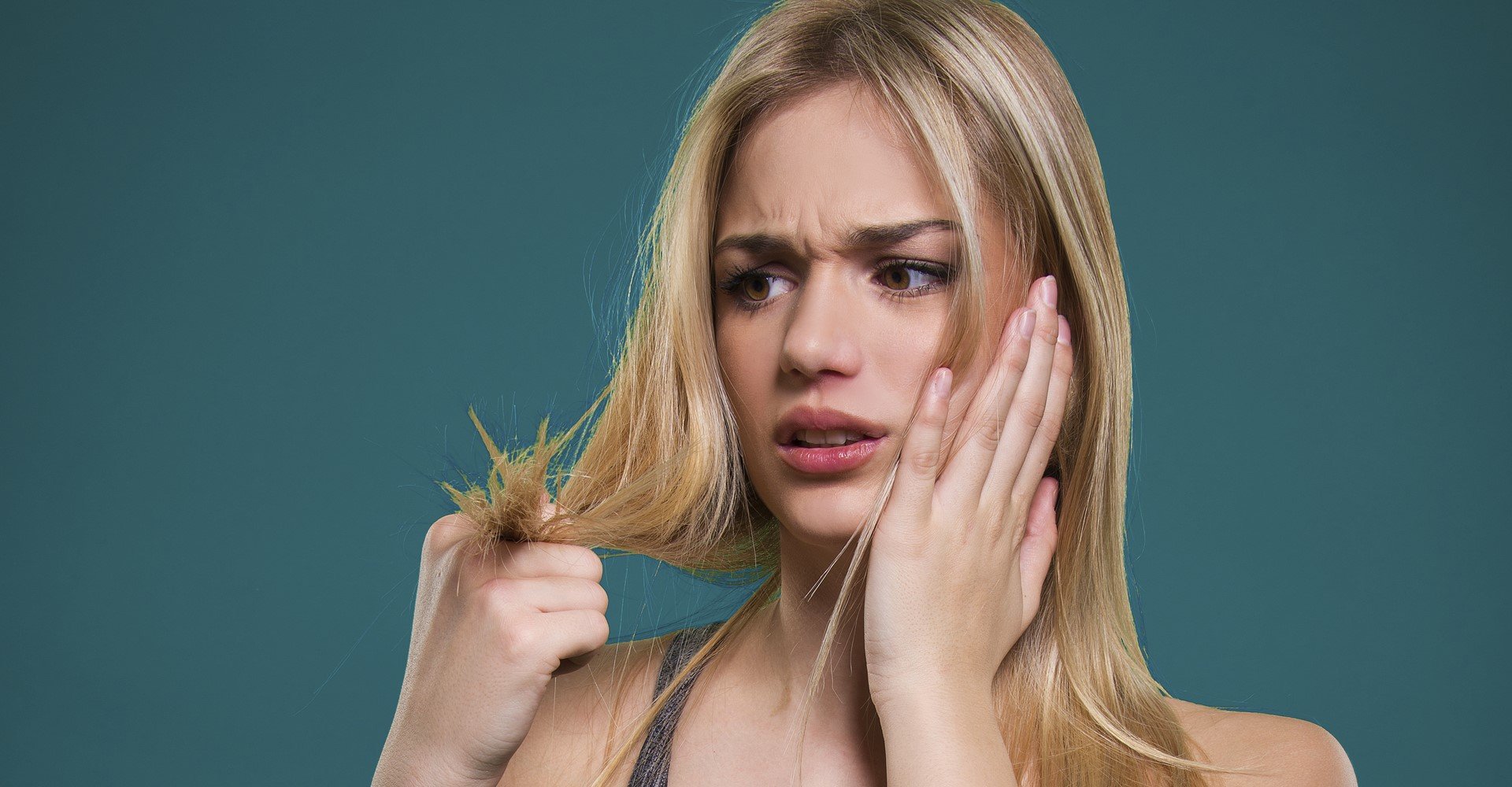 Modelo branca e loirando analisando as pontas de seu cabelo