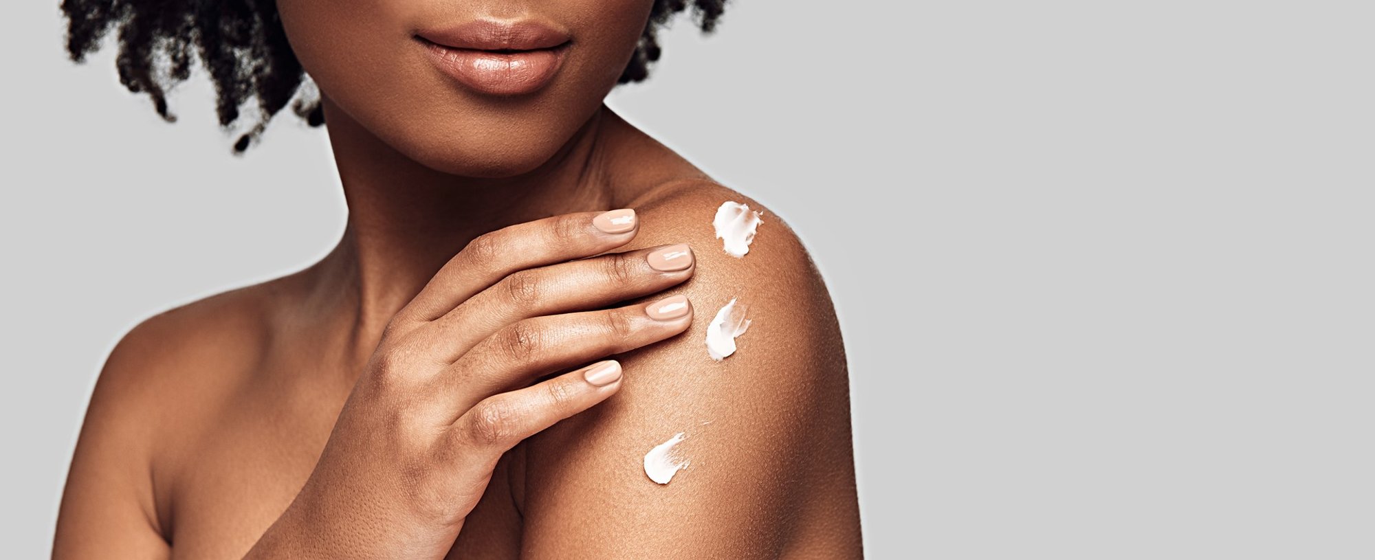 Modelo negra com creme no ombro