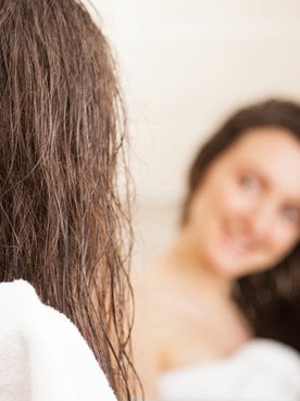 Modelo branca secando seus cabelos com toalha branca