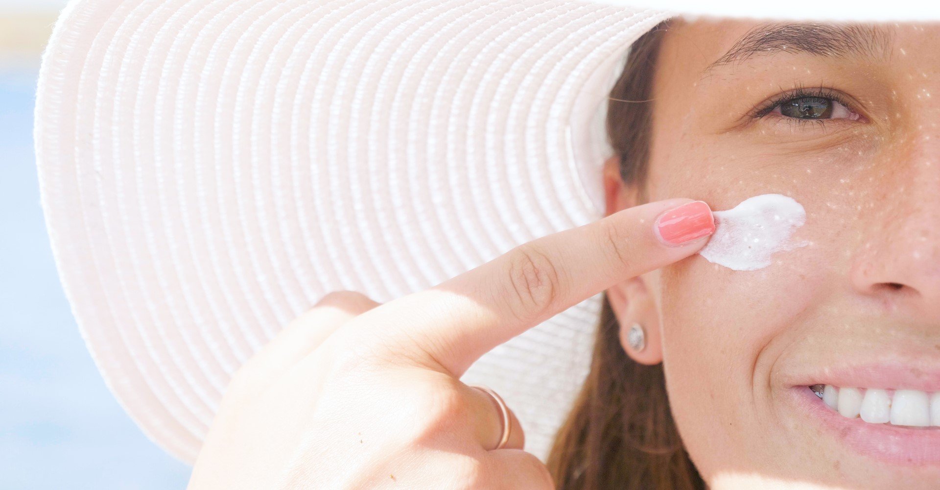 Modelo branca passando protetor solar no rosto