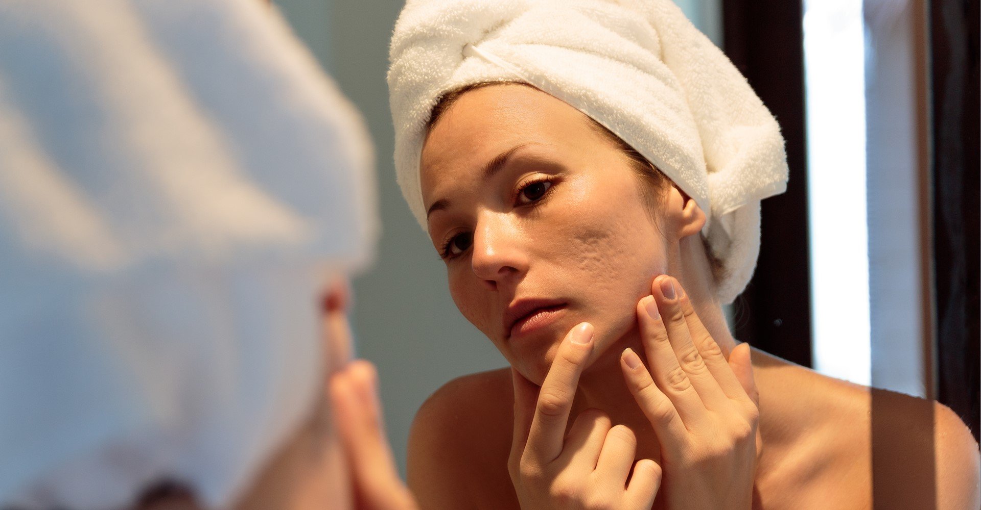 Modelo branca analisando seu rosto no espelho