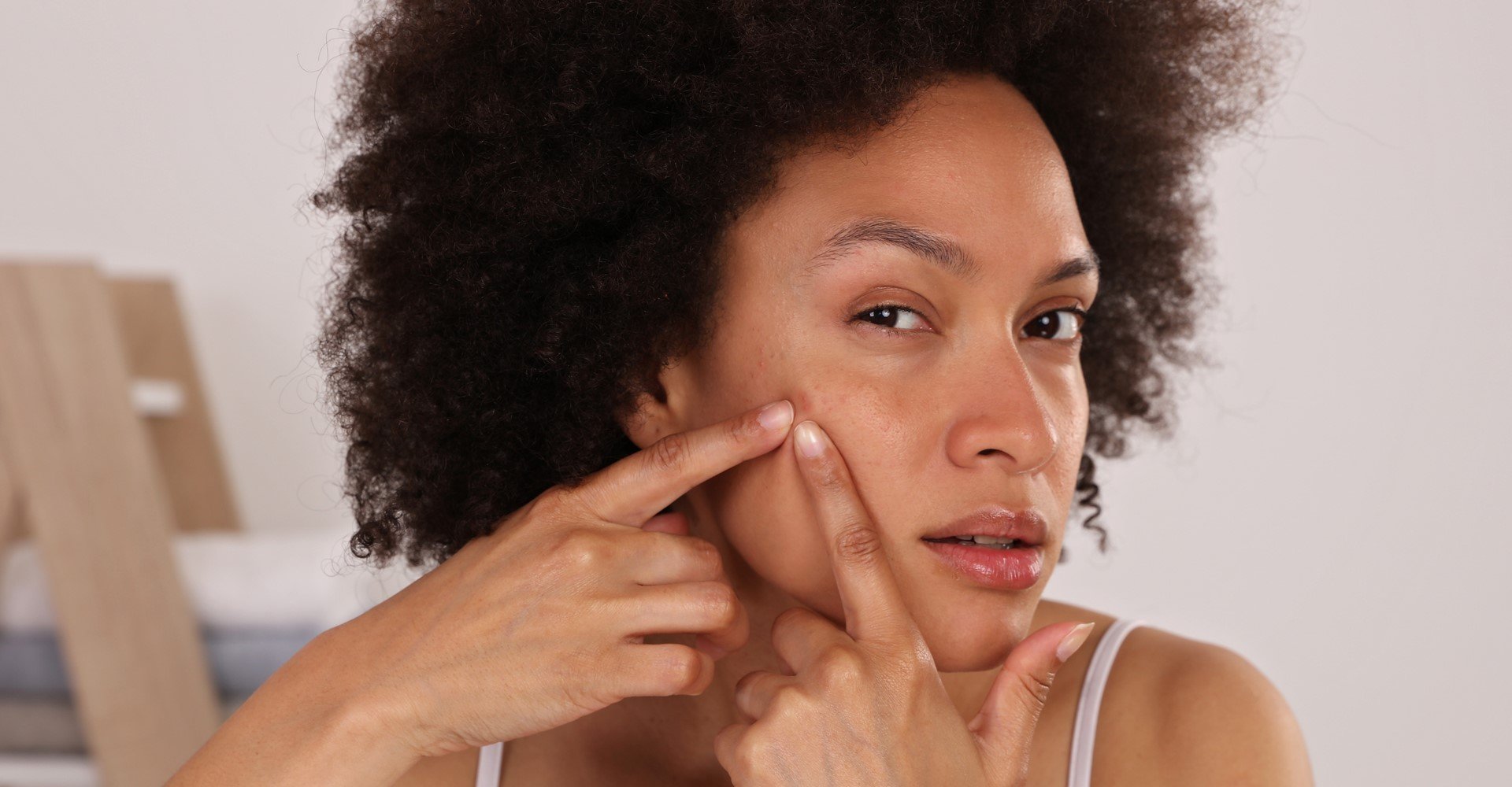 Modelo negra apertando acne do rosto