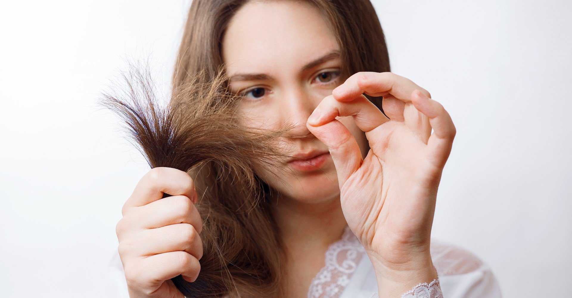 Modelo branca analisando as pontas do seu cabelo