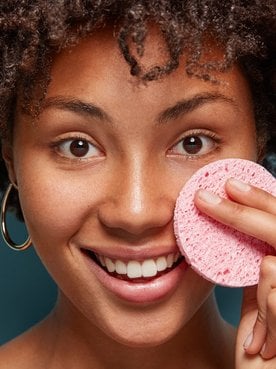 Modelo negra passando esponja no rosto