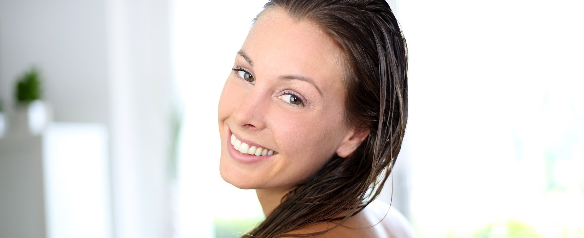 Mulher Sorrindo Enquanto Passa Condicionador No Seu Cabelo