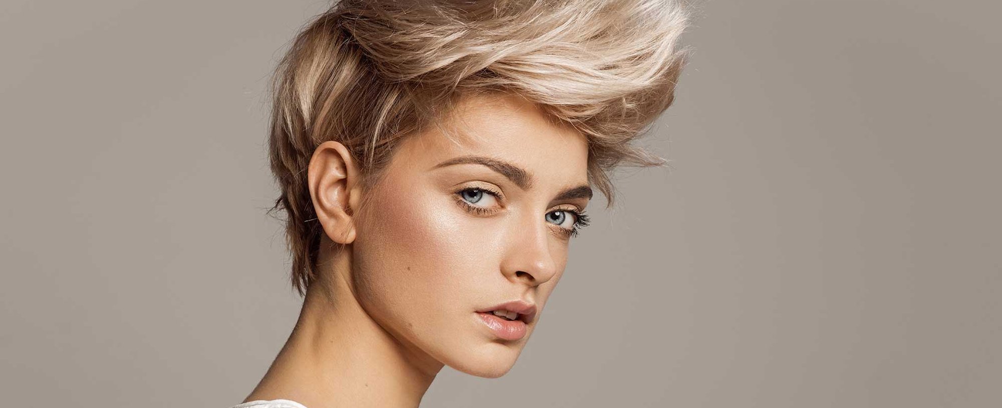 Modelo loira com cabelo curto e um topete curvado para cima