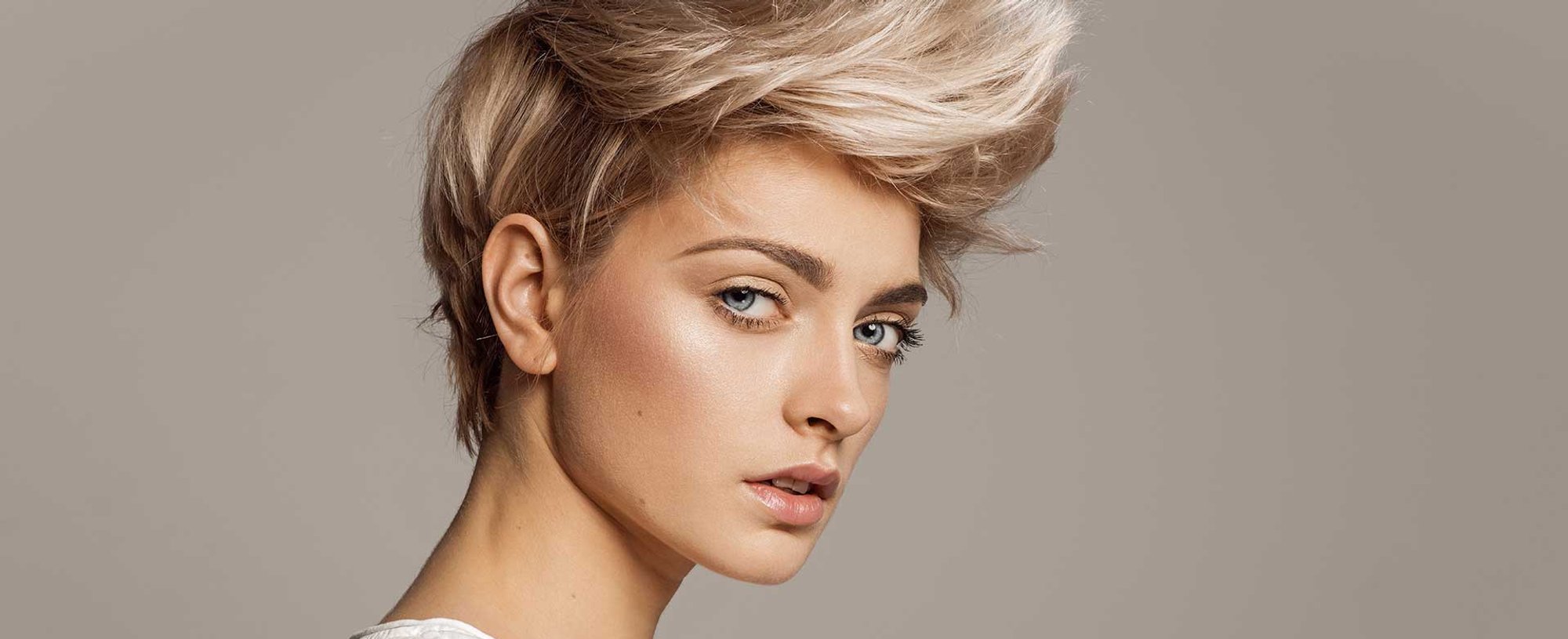 Modelo loira com cabelo curto e um topete curvado para cima