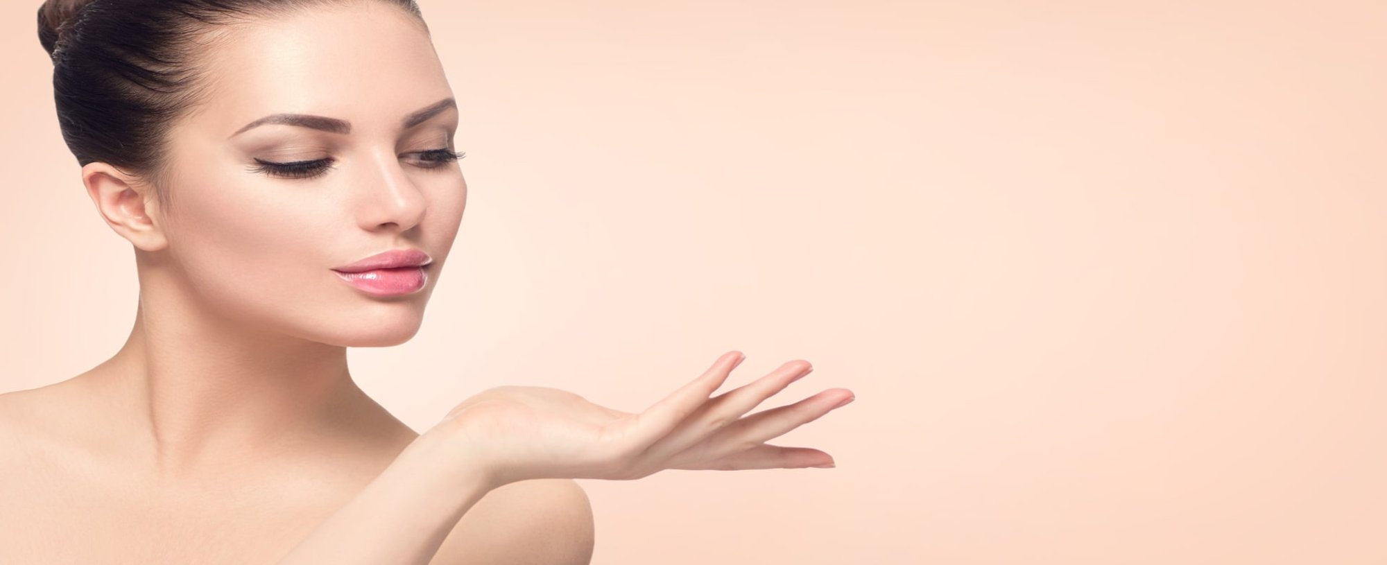 Modelo branca  com o cabelo amarrado de coque olhando para seu braço