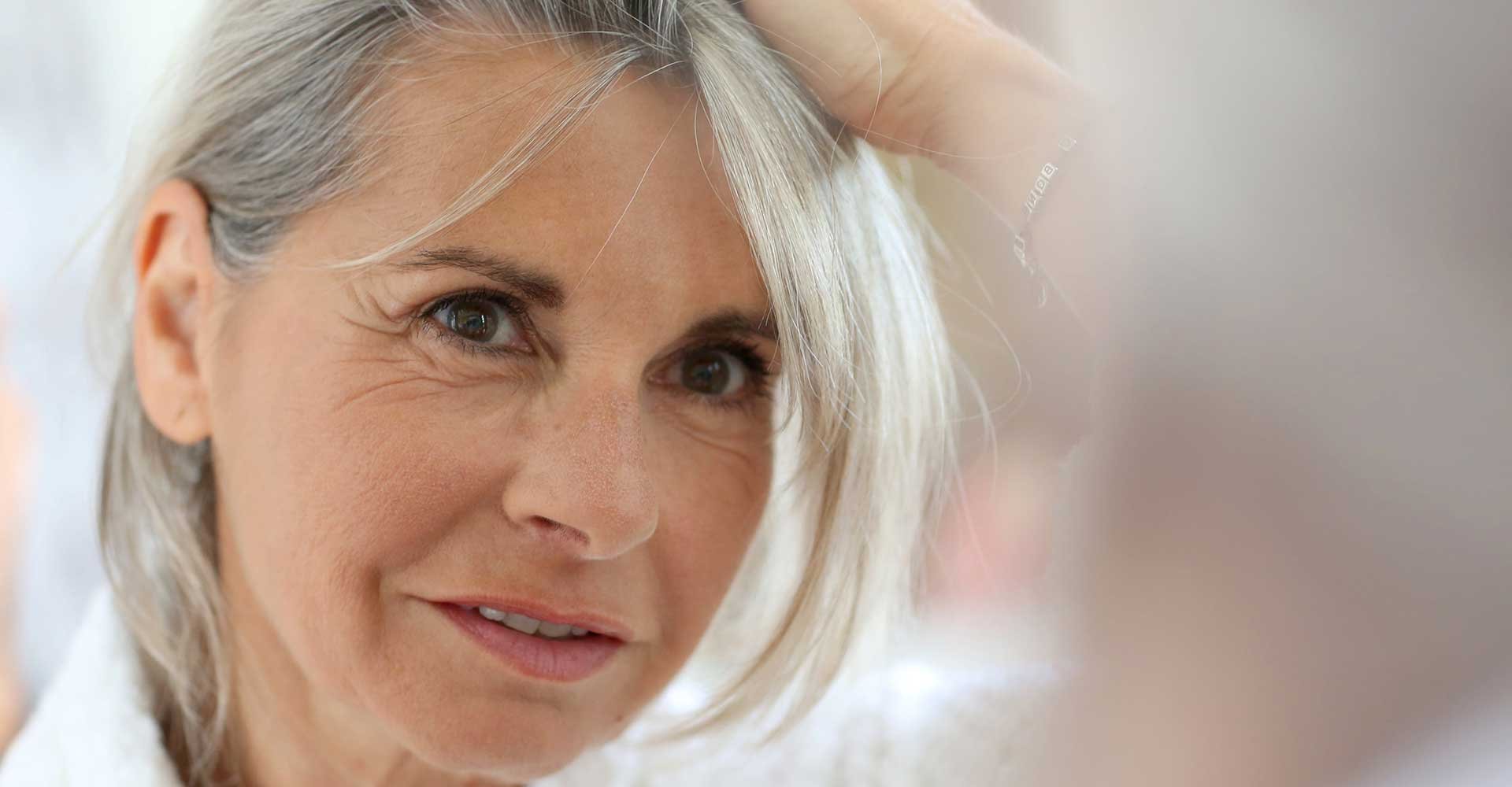 Mulher idosa verificando seus cabelos castanhos