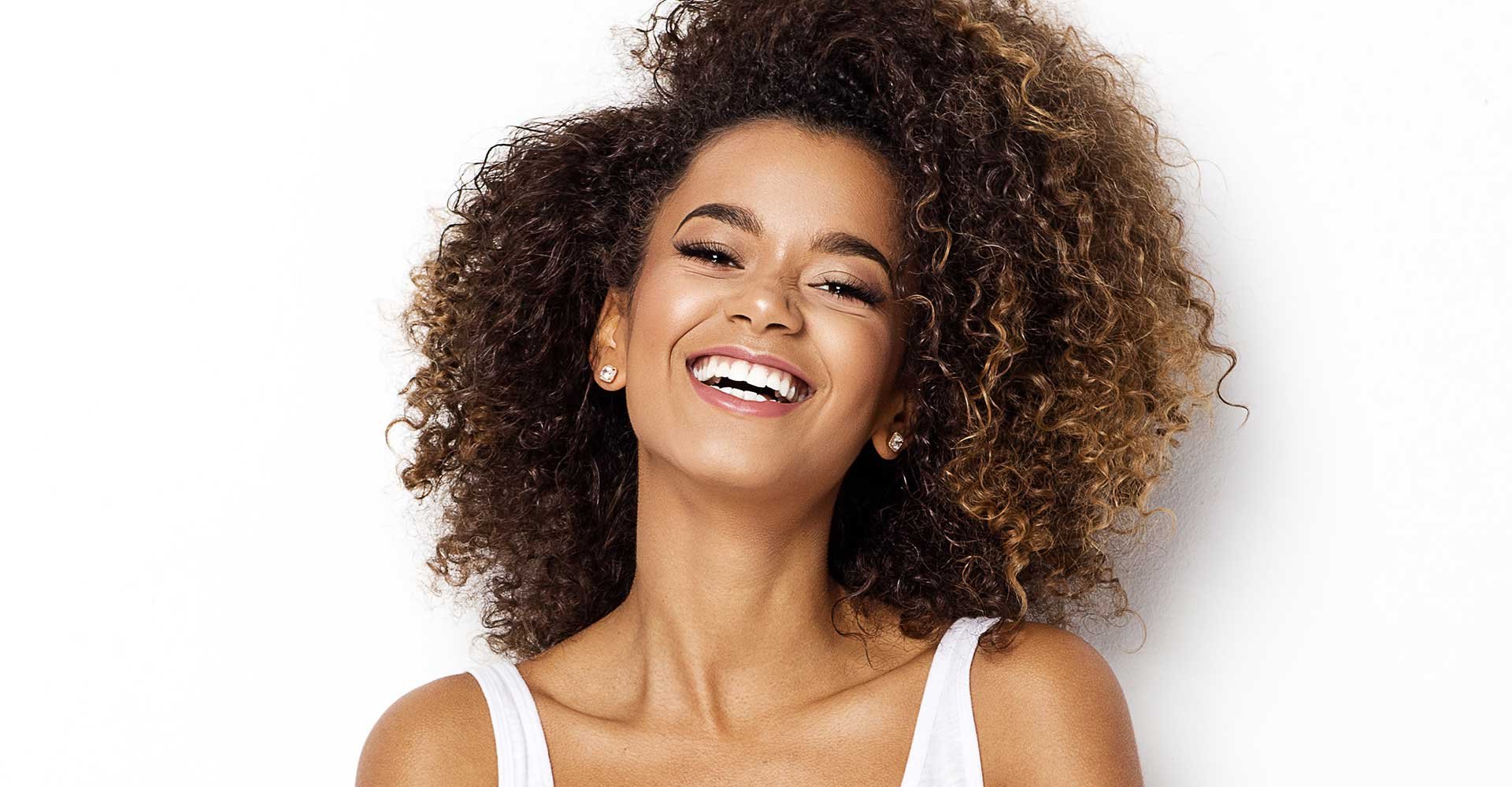 Modelo morena com cabelos cacheados com luzes nas pontas