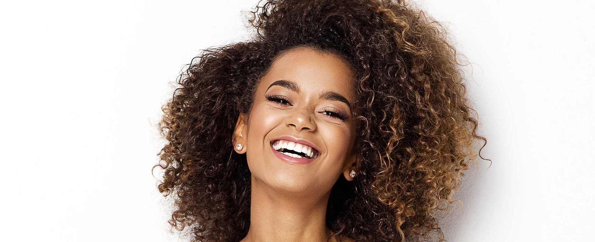 Modelo morena com cabelos cacheados com luzes nas pontas