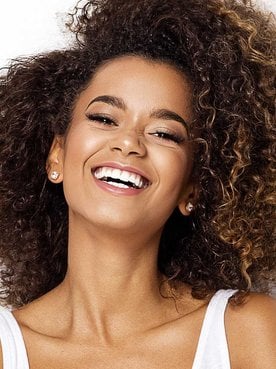 Modelo morena com cabelos cacheados com luzes nas pontas