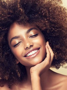 Modelo morena com cabelos cacheados e volumosos