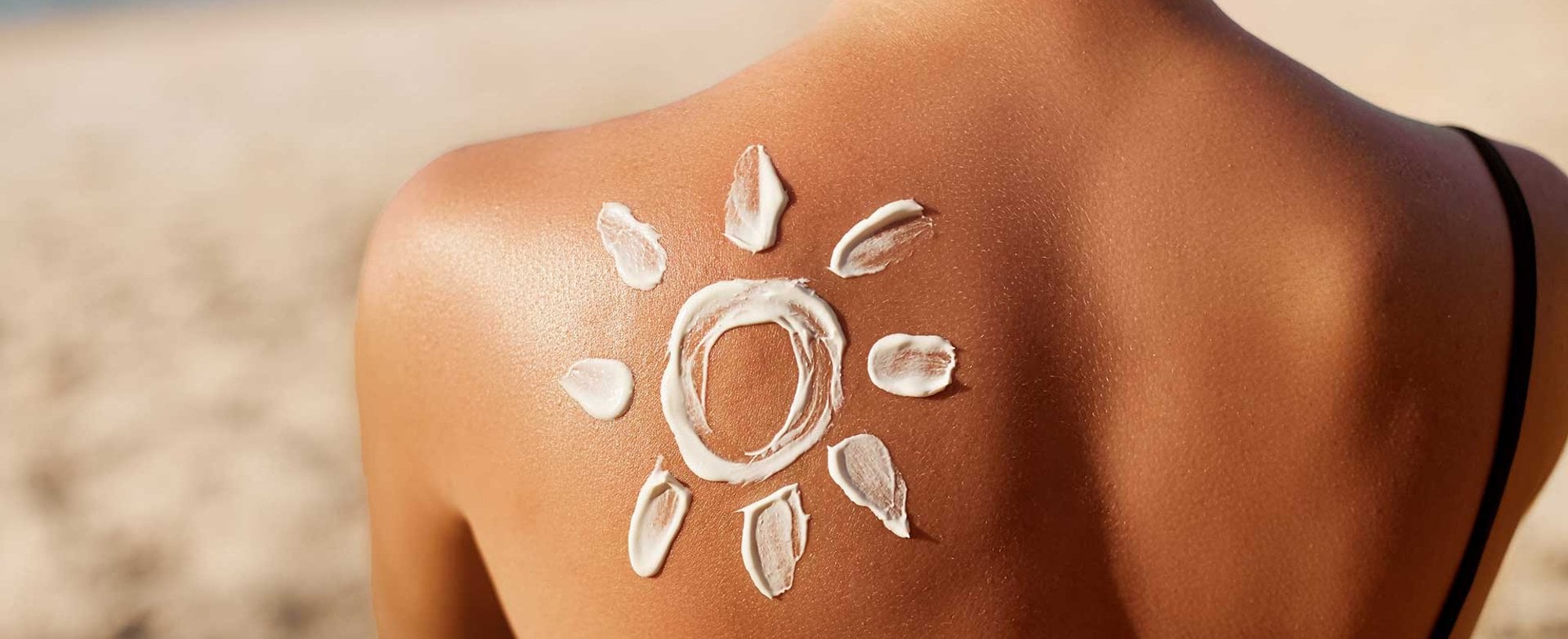 Modelo de costas com um sol desenhado com creme