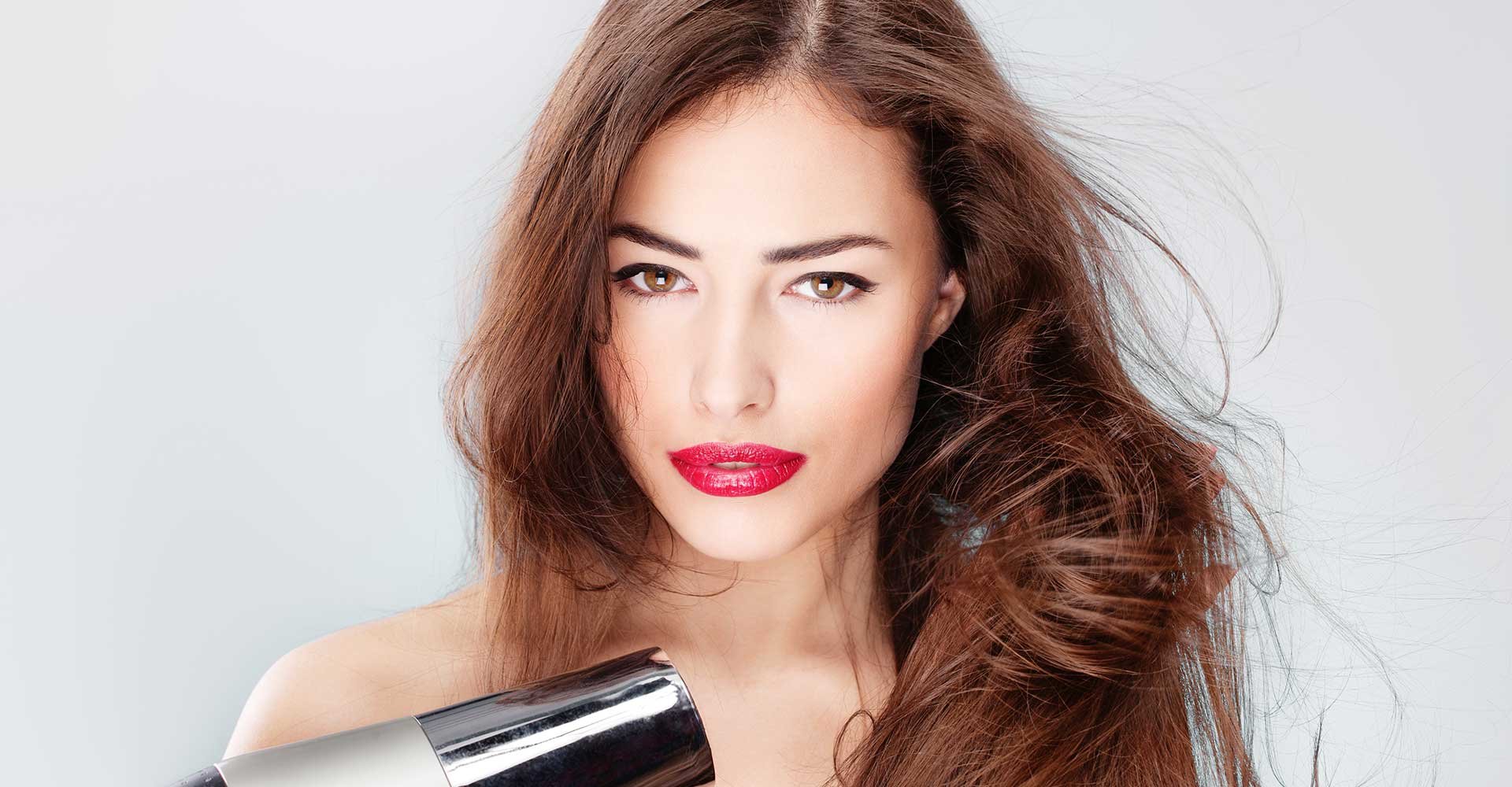 Modelo secando seu cabelo com ajuda de um secador