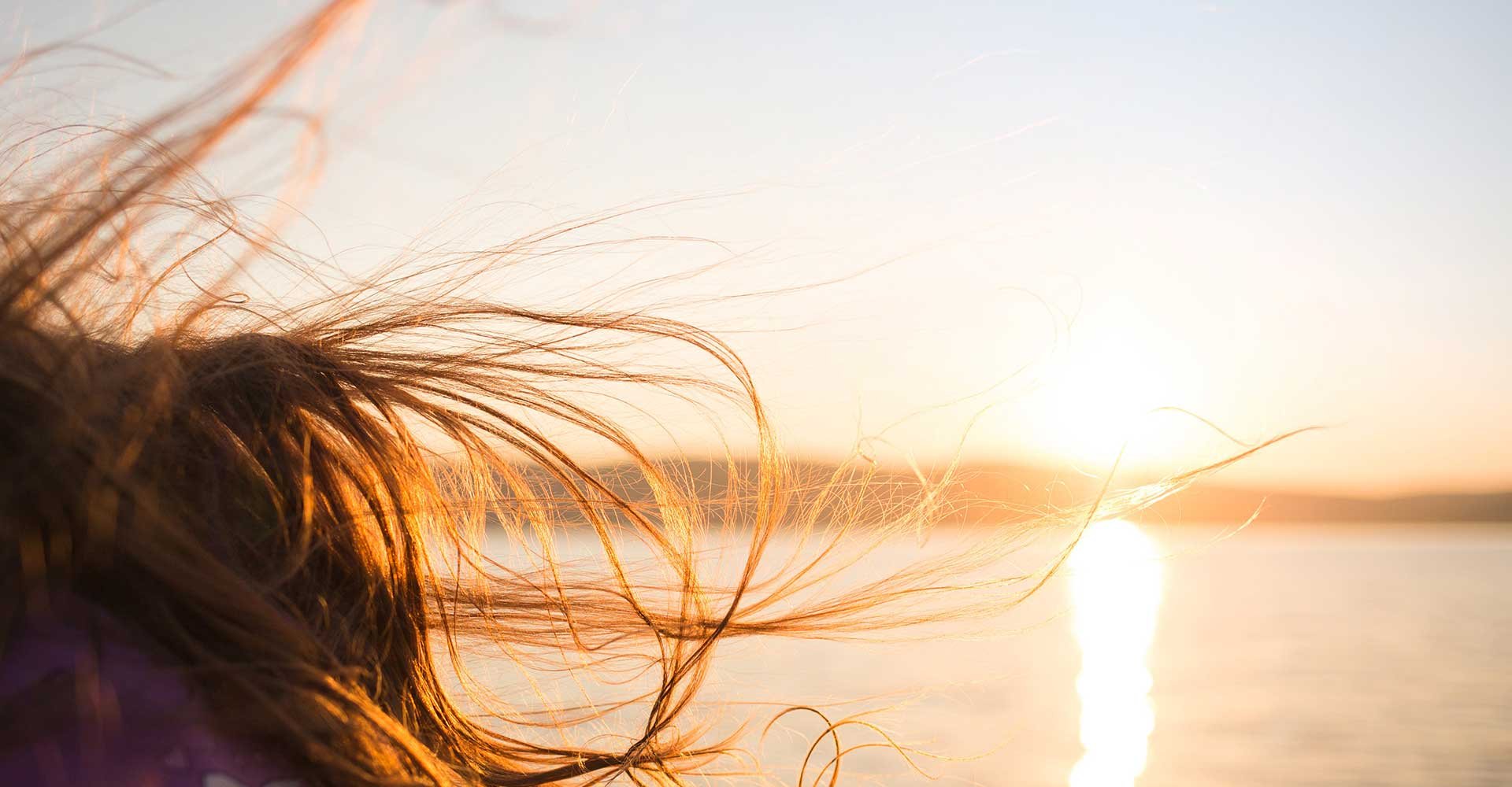 Mulher Com Cabelo Castanho Ao Vento Com Sol No Fundo