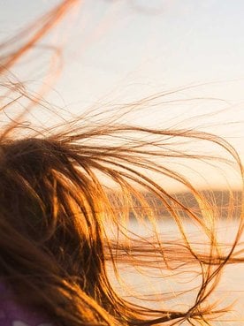 Mulher Com Cabelo Castanho Ao Vento Com Sol No Fundo