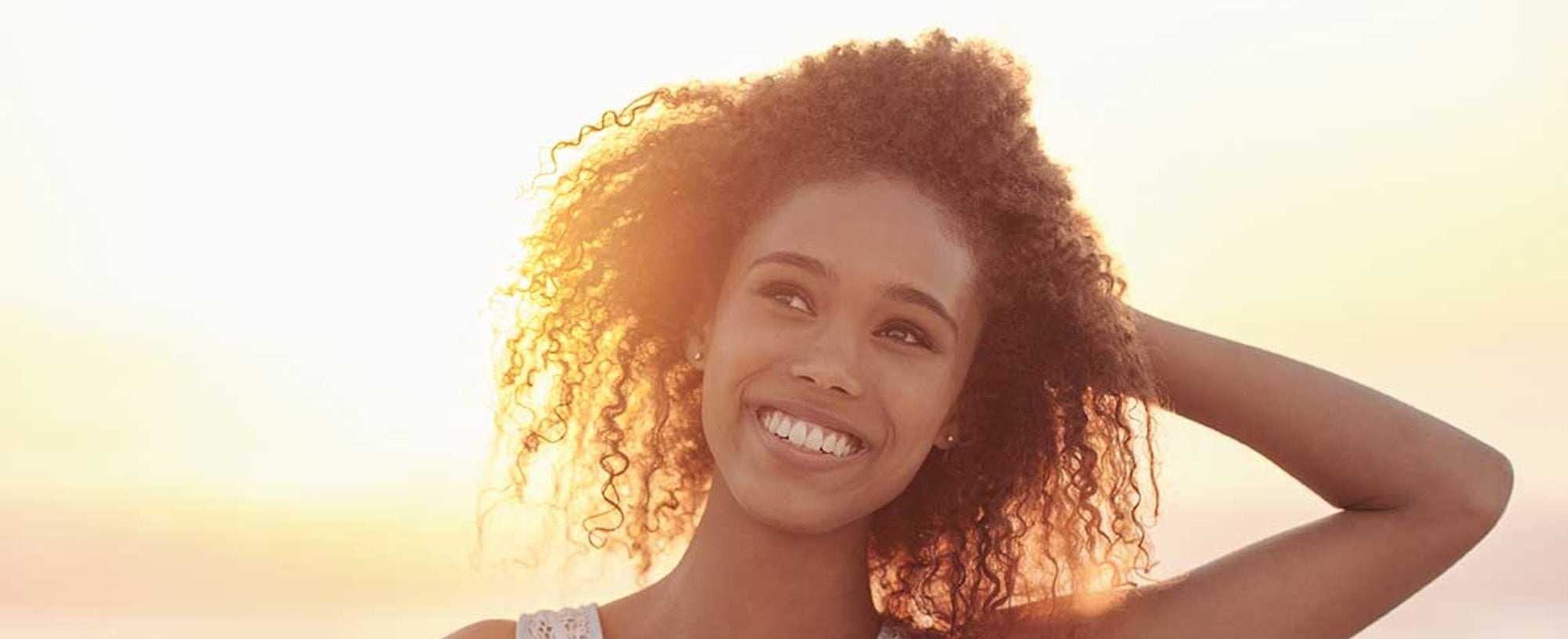 Modelo cacheada e morena enfrente ao som sorrindo