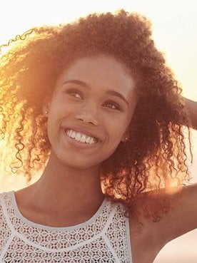 Modelo cacheada e morena enfrente ao som sorrindo