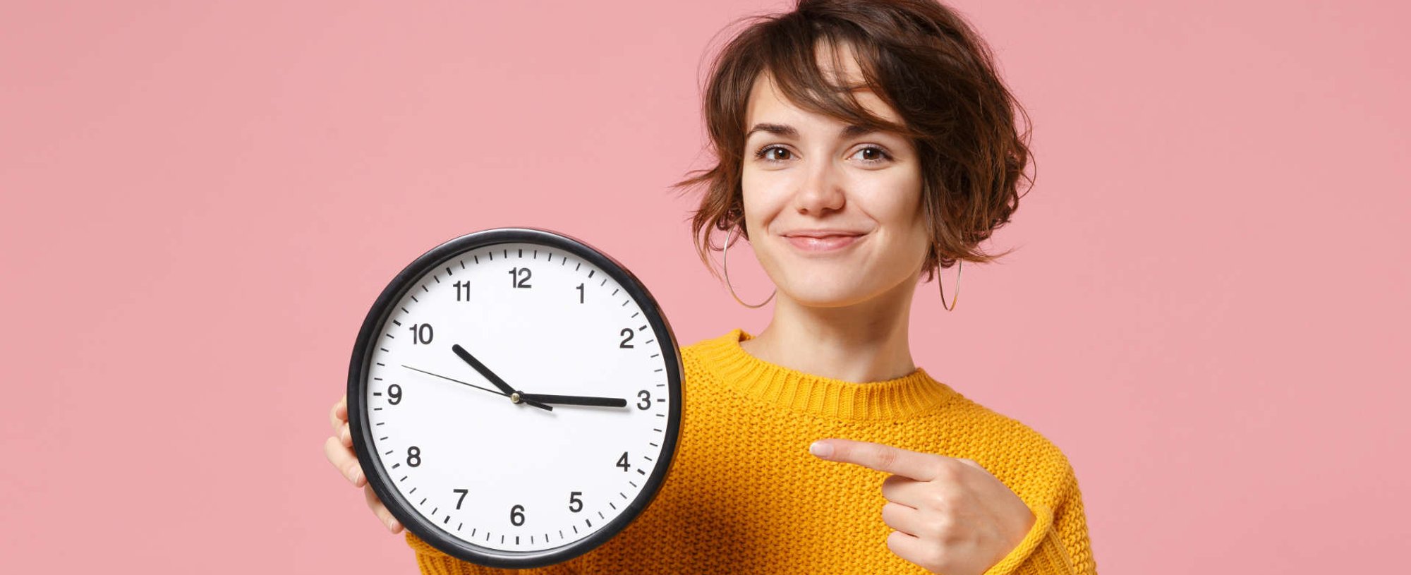 mulher aponta para um relógio analógico