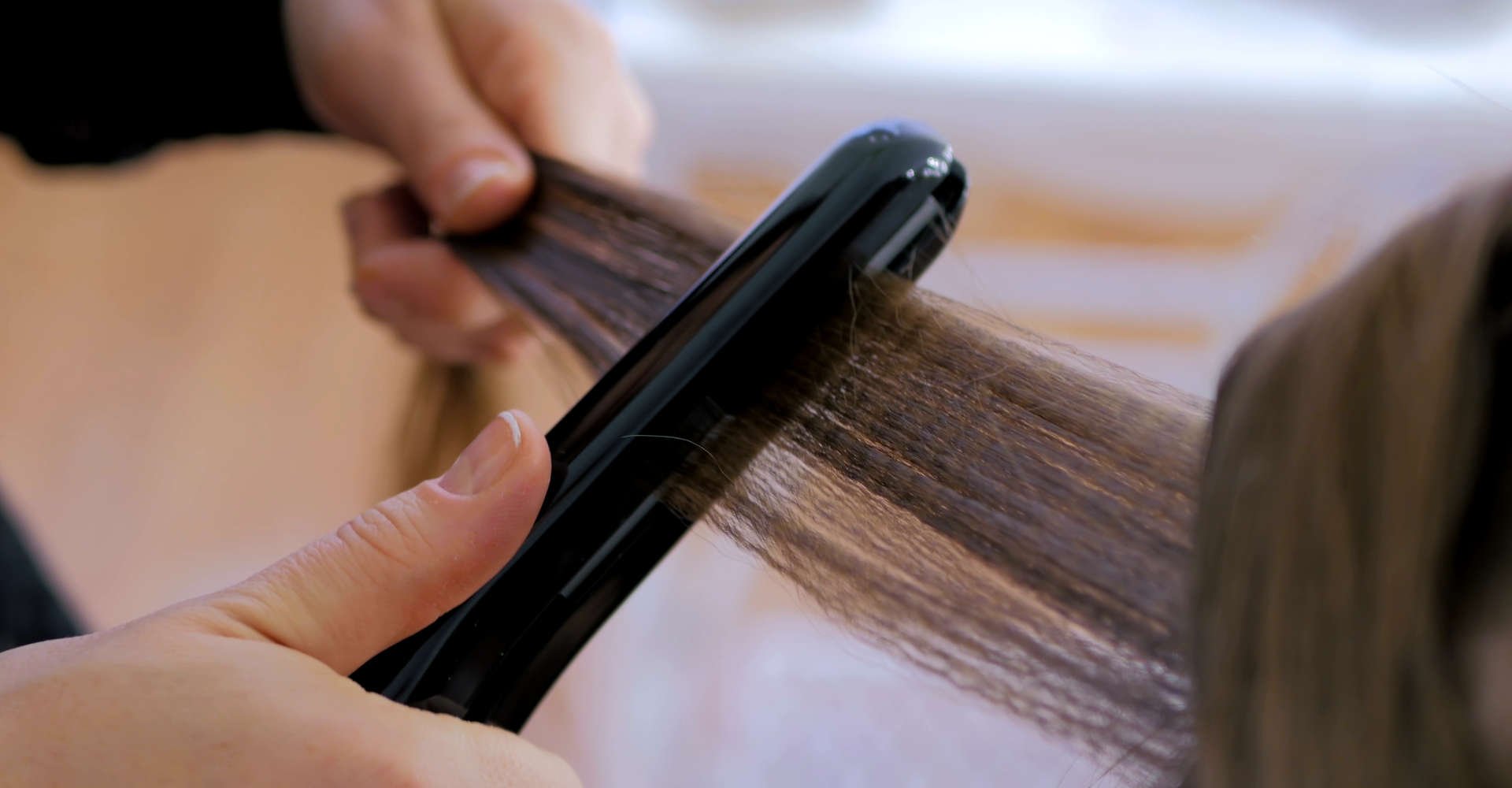 mulher passando chapinha no cabelo de outra mulher