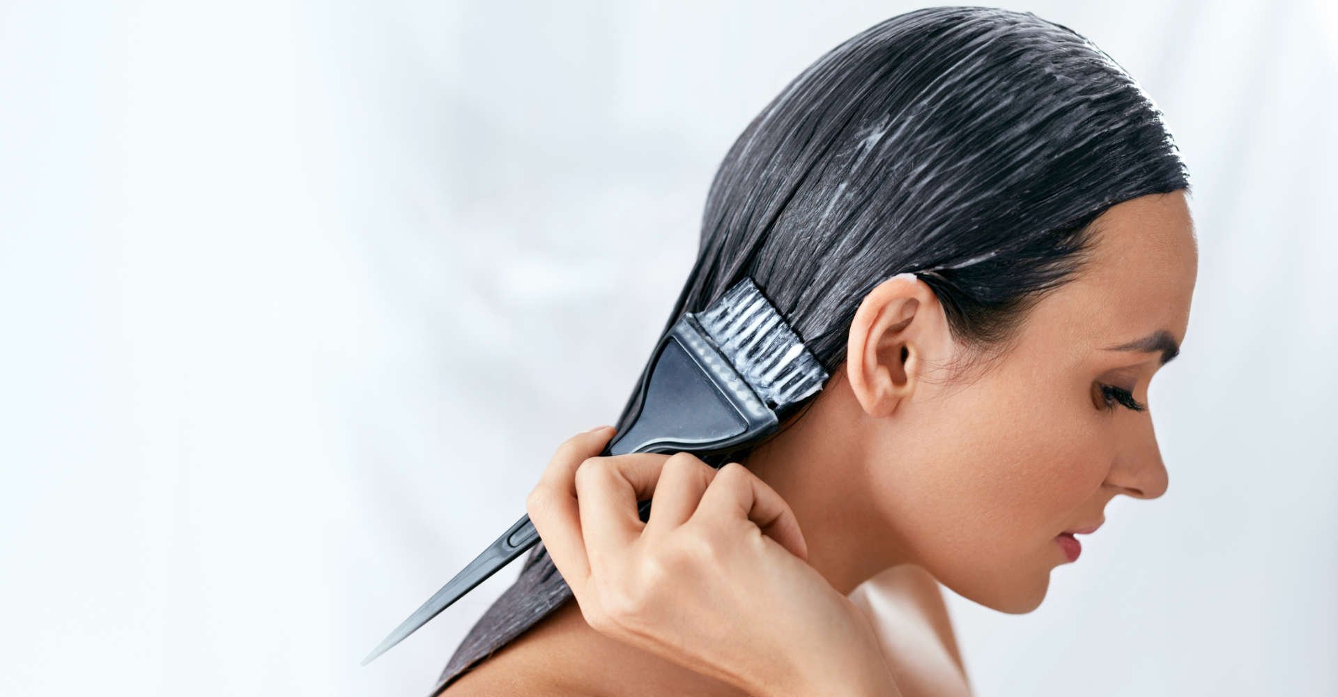 mulher passando mascara no cabelo escuro