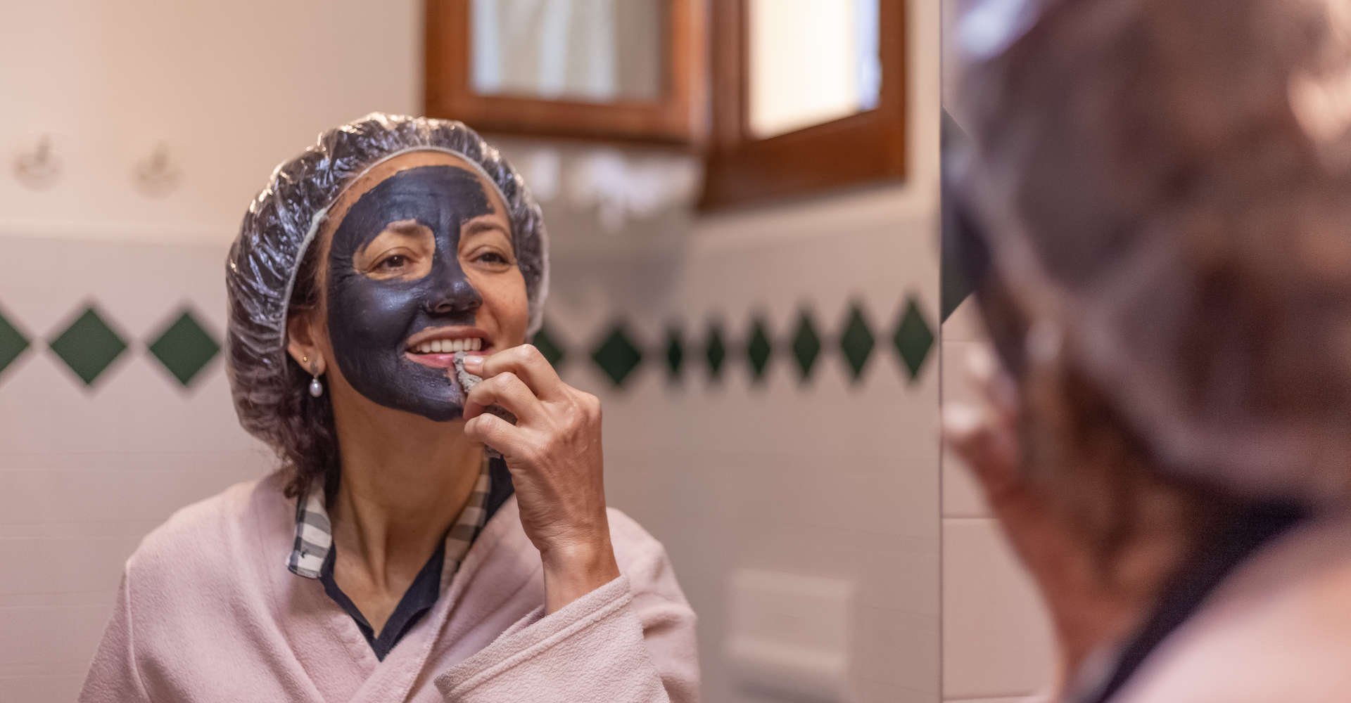 mulher utilizando máscara de argila em frente ao espelho