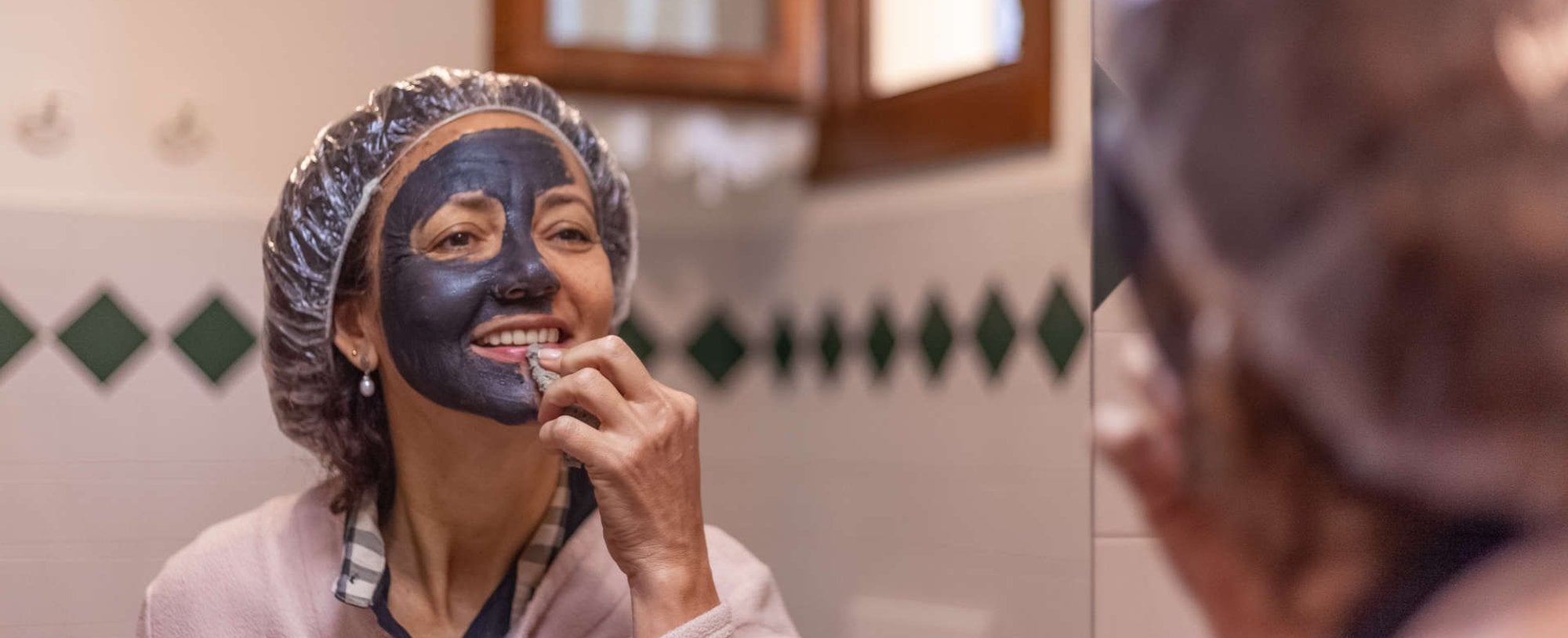 mulher utilizando máscara de argila em frente ao espelho