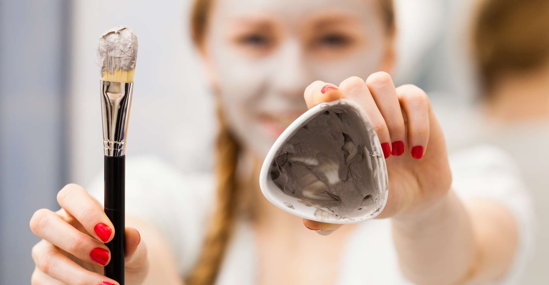 mulher segurando creme de argila para passar na pele do rosto