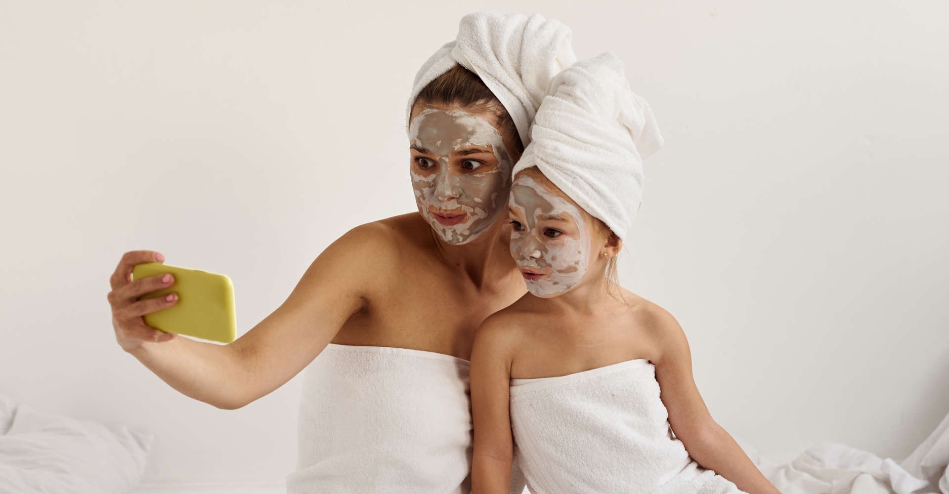 mãe e filha tirando uma "selfie" usando máscara de argila