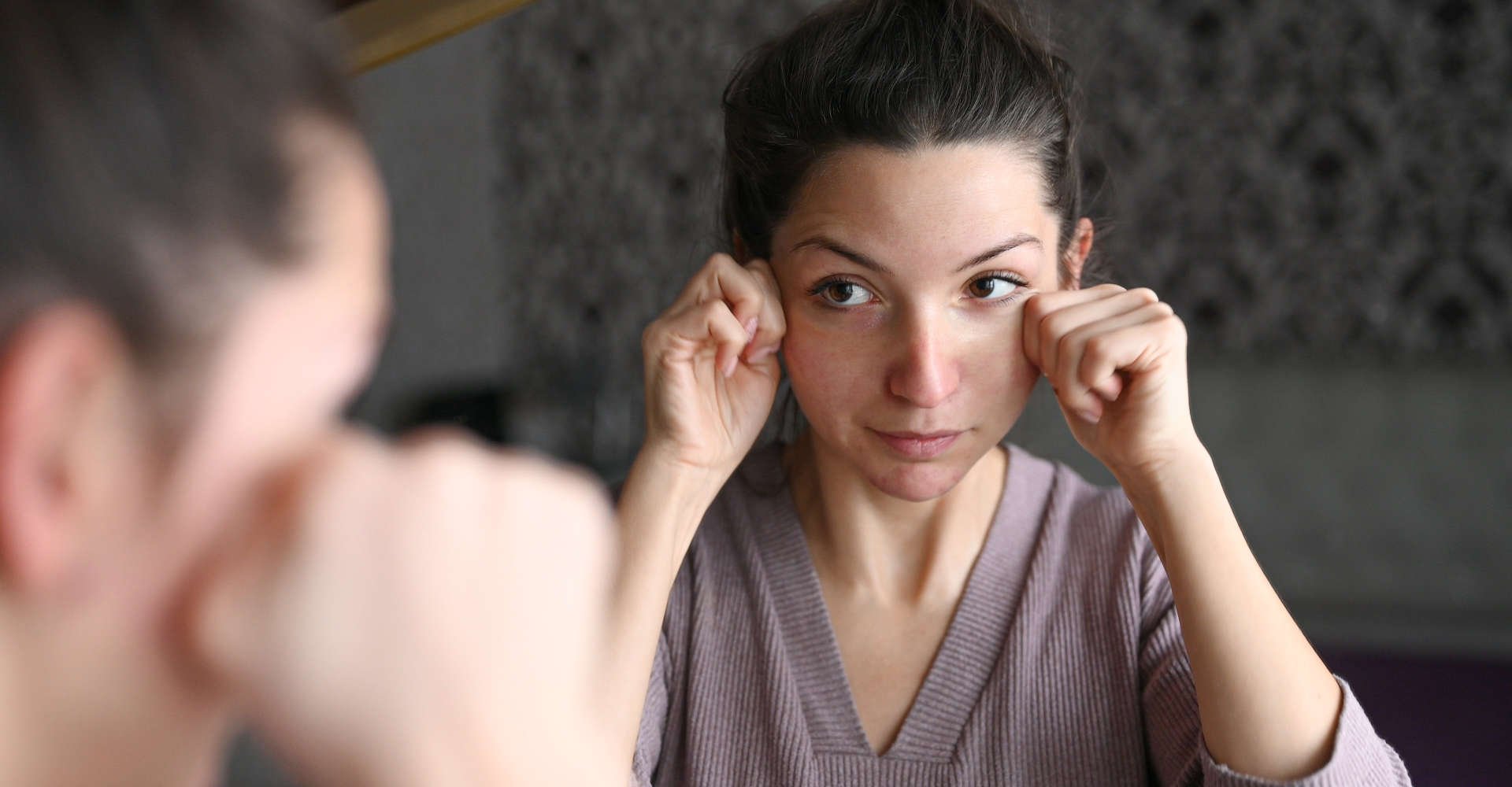 mulher exercitando o rosto em frente ao espelho