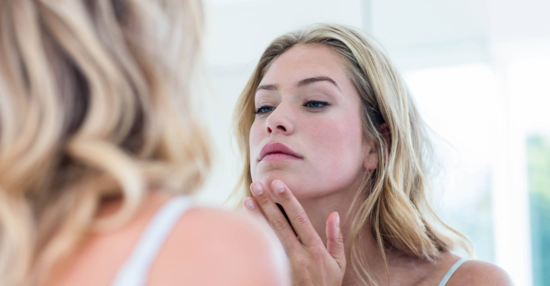 mulher preocupada com a pele frente ao espelho