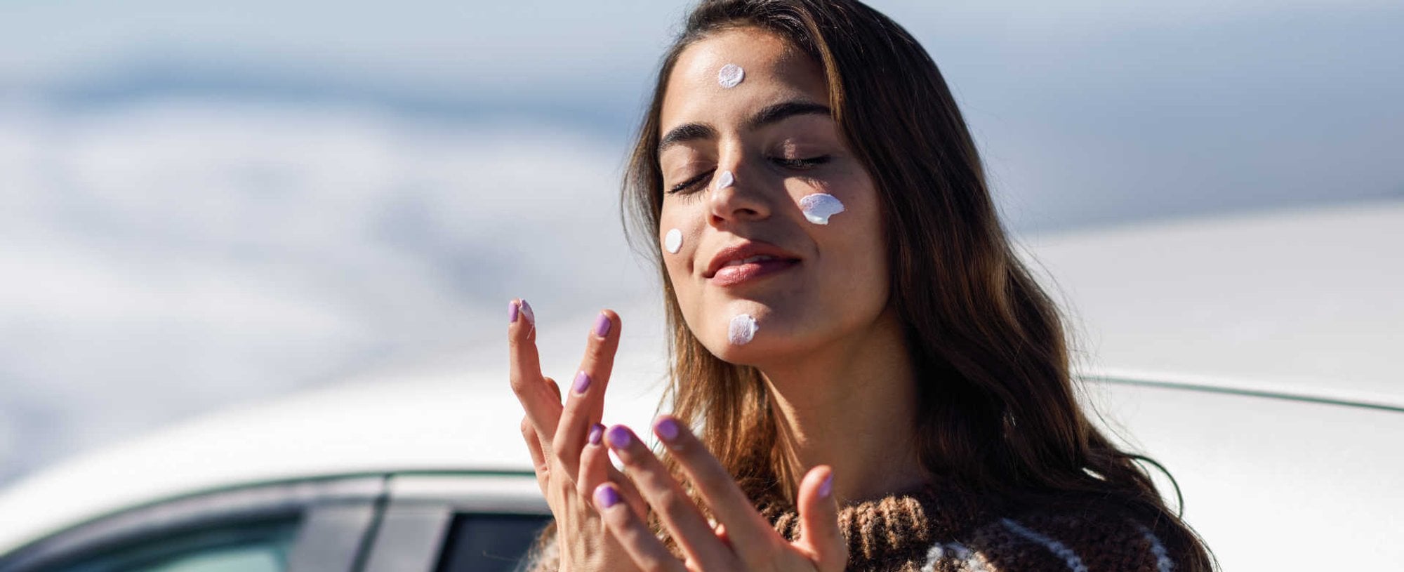 Modelo branca passando protetor solar no rosto