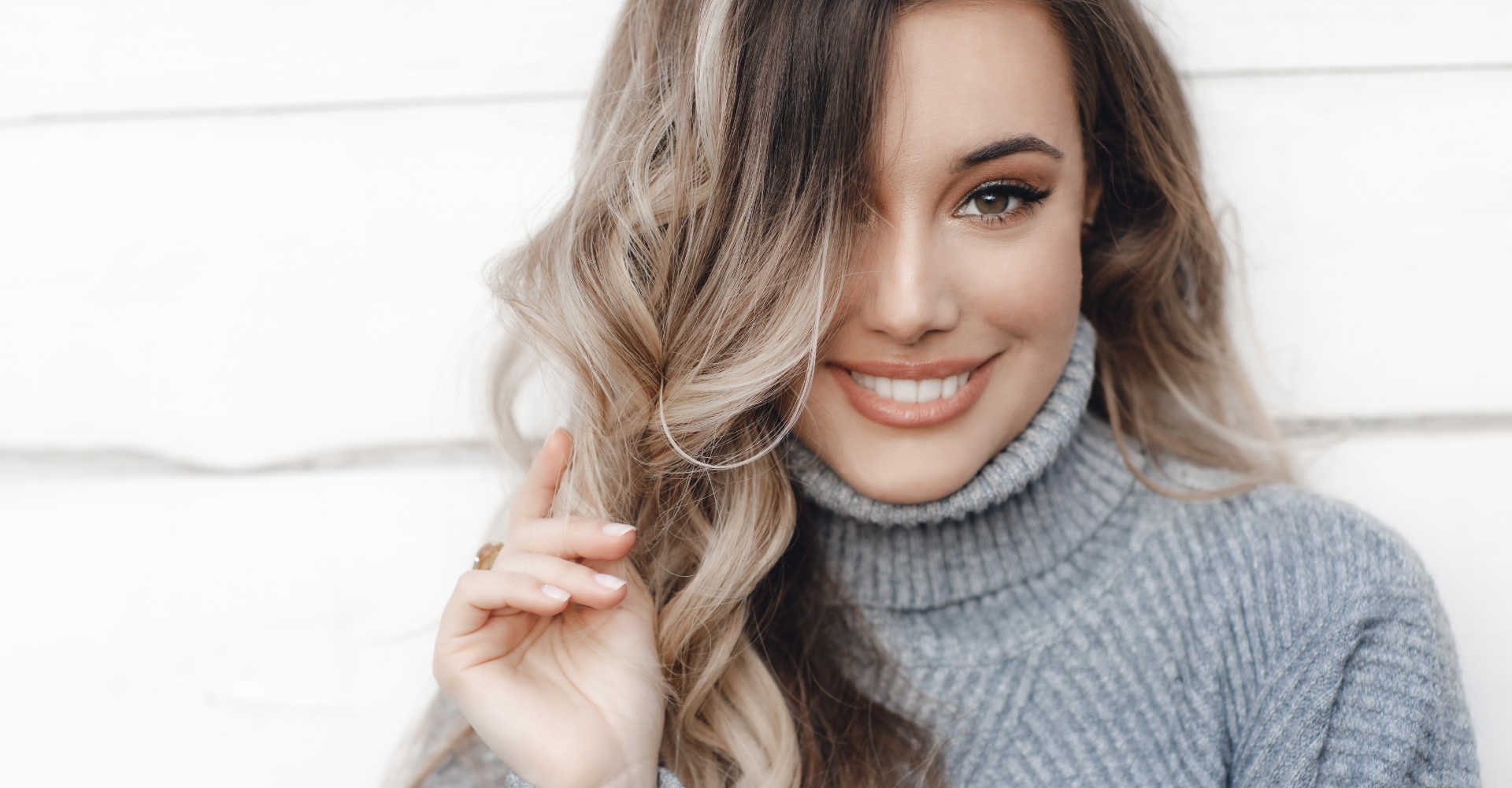 Modelo branca sorrindo com mechas loiras no cabelos