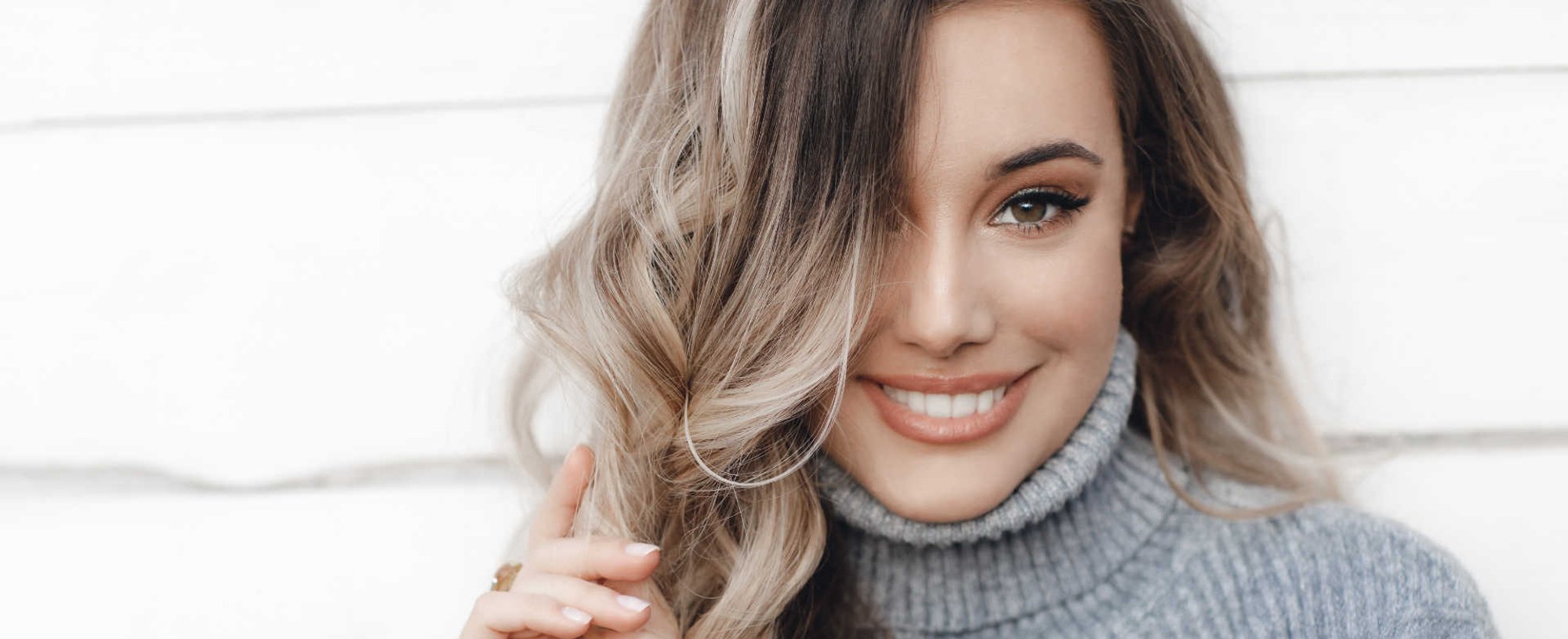 Modelo branca sorrindo com mechas loiras no cabelos