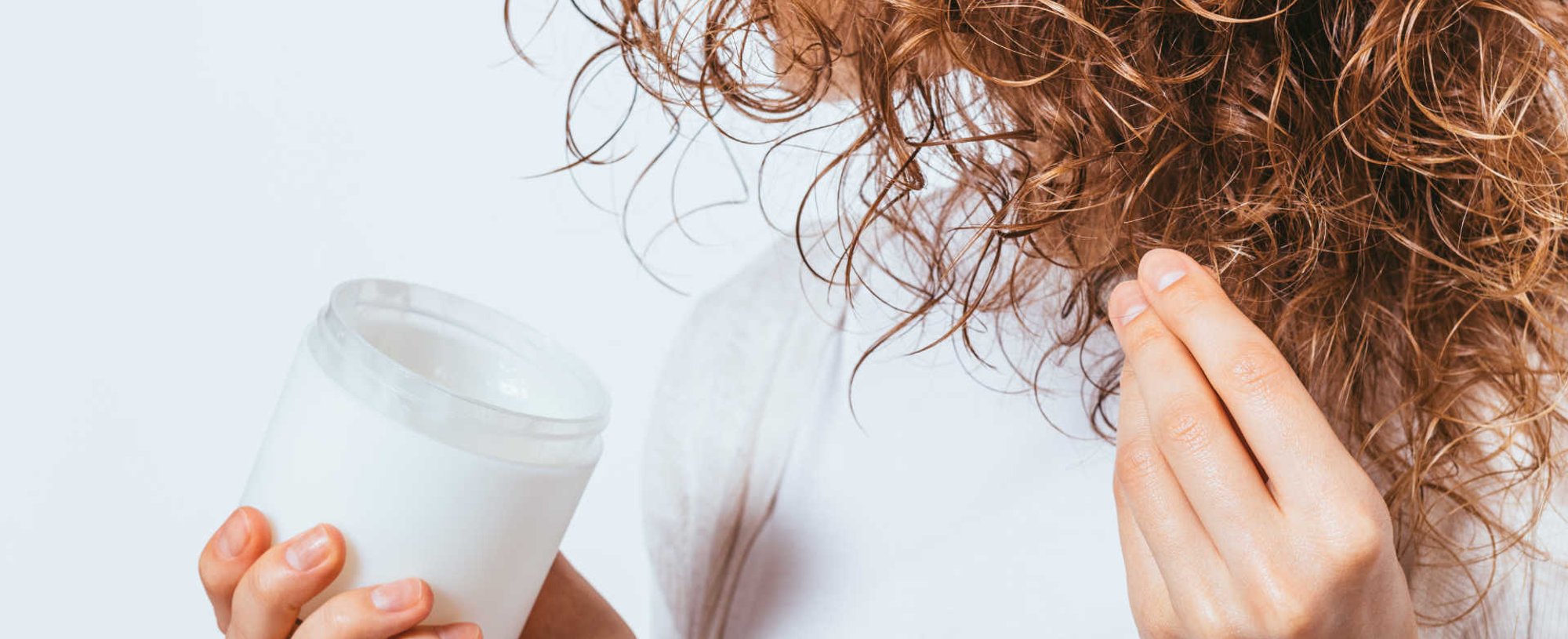 Modelo passando creme em seus cachos