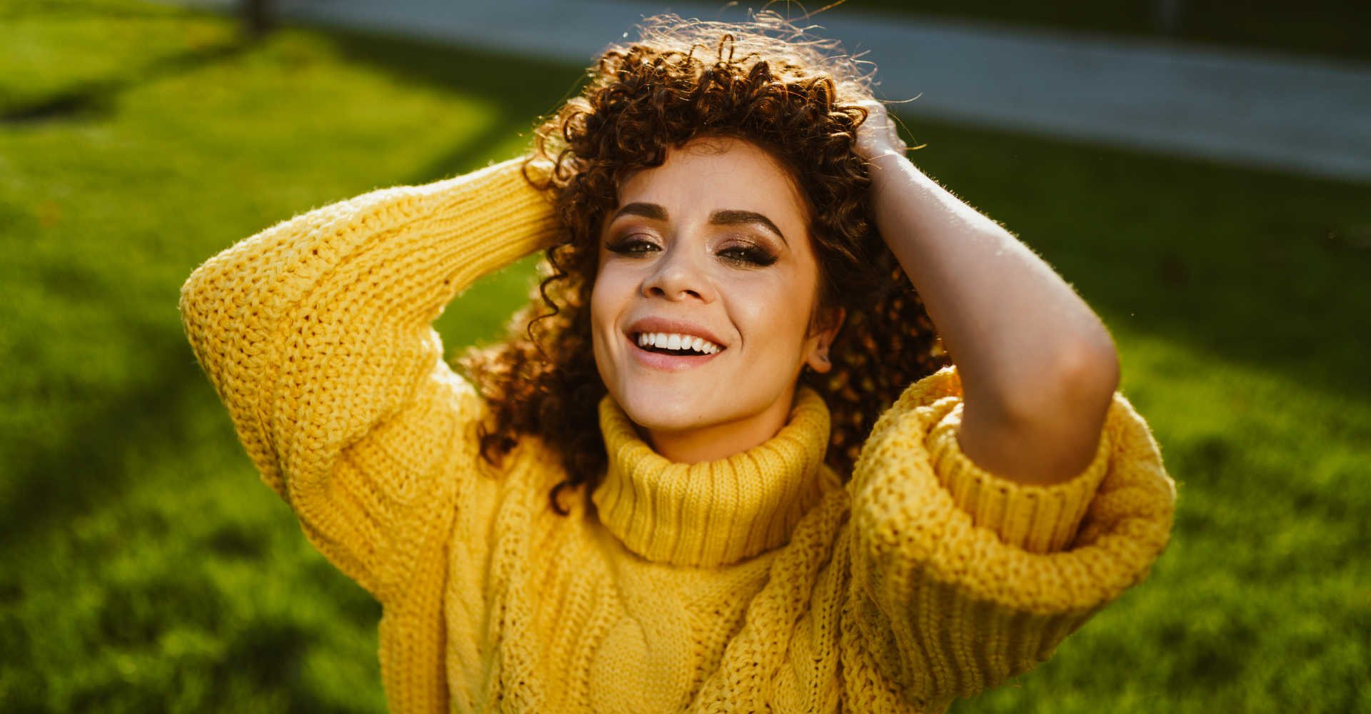 Modelo branca sorrindo com cabelo cacheado