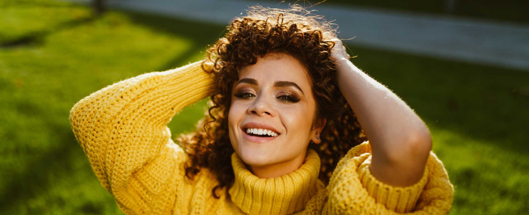 Modelo branca sorrindo com cabelo cacheado